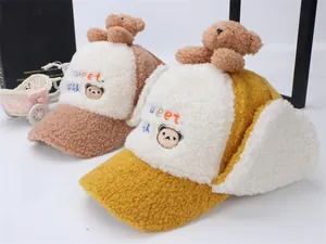 Dettaglio dei cappelli di peluche con paraorecchie zenzero e kaki e ricamo orsetto