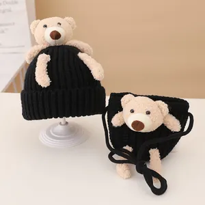 Close-up of black knitted baby hat and mini bag set with cute 3D plush teddy bear detail