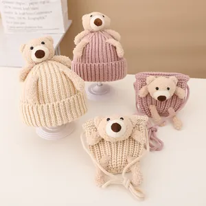Detail of knitted baby hats and matching crossbody bags with cute plush bear accents