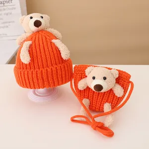 Detail of orange knitted baby hat and bag set with cute plush bear decorations