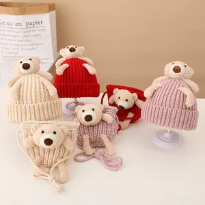 Close-up of knit hats and matching bear bags in cream, red and pink for children