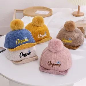 Détail de casquettes bébé en polaire avec pompons et broderie organique en cinq couleurs