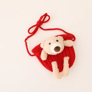 Close-up of red knit child bag with cute plush bear ornament and textured stitching