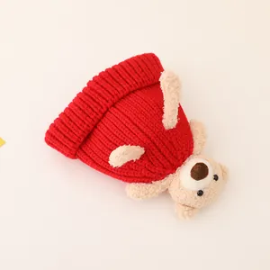 Detail of red knit hat for toddlers featuring a cute plush bear ornament and ribbed texture