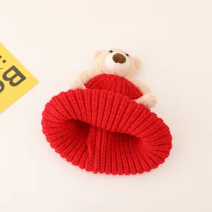 Detailed view of red knitted baby hat featuring a cute plush bear and warm winter texture