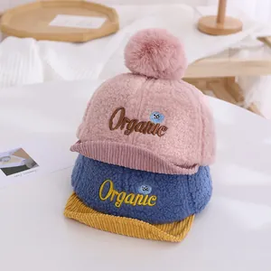 Vue détaillée des bonnets en polaire rose et bleu avec pompons et broderie organic