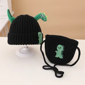 Detail of black knitted beanie and crossbody bag with 3D green dinosaur character
