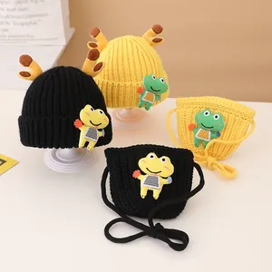 Detail of knit child hat and bag set with brown antlers and cute cartoon frog patch