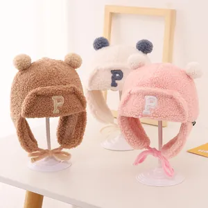 Close-up of children's fleece trapper hats with pom-poms in brown, cream, and pink
