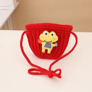 Detail of red knit kids crossbody bag featuring a cute yellow cartoon frog patch