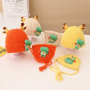 Detail of knitted baby hat and scarf set featuring deer antlers and frog patches