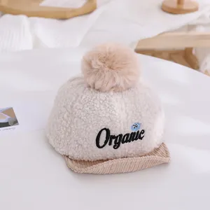 Gros plan détaillé sur casquette hiver bébé avec pompon peluche et broderie organic
