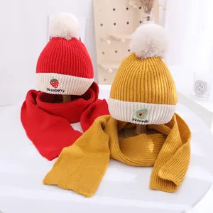 Detailed view of warm winter knit hats and scarves with cute strawberry and avocado embroidery