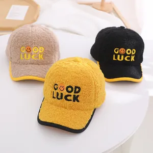 Three plush kids baseball caps with Good Luck embroidery and smiley face on a table