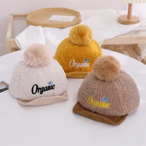 Vue détaillée de bonnets en polaire pour bébés en crème, jaune et marron avec broderie