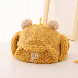 Close-up of yellow children winter trapper hat with soft plush texture and letter P patch