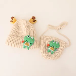 Close-up of children's knitted hat and bag set with deer antlers and frog patch