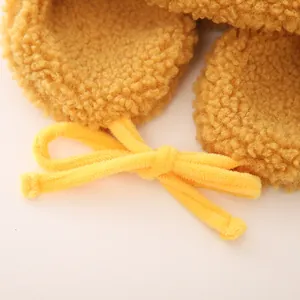 Detailed close-up of warm yellow fleece fabric with velvet drawstring bow for kids' winter hat