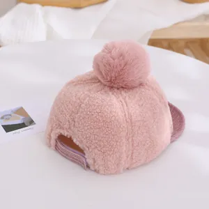 Détail d'une casquette en polaire rose pour bébé avec pompon en fourrure et bord velours