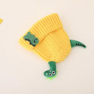 Detailed close-up of yellow knit beanie with cute green 3D dinosaur decor and soft texture