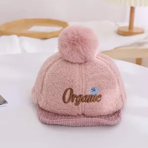 Détail de la casquette bébé rose en polaire avec broderie organique et pompon doux
