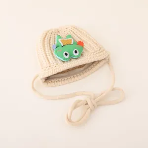 Detail of beige knitted children's crossbody bag with green frog patch and zipper