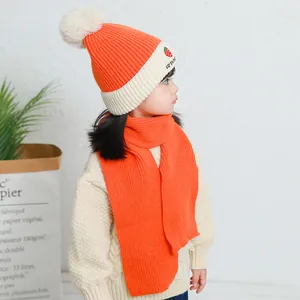 Detail of children's knit hat with strawberry embroidery and orange scarf set