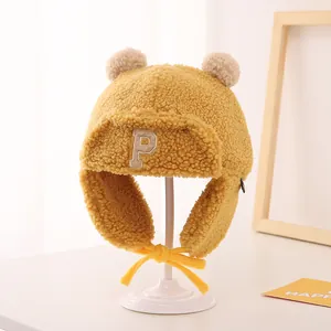 Detailed view of ginger yellow lamb velvet trapper hat with furry ears and letter P embroidery