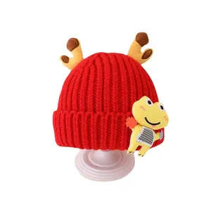 Red knit kids hat with cute reindeer antlers and cartoon patch for autumn and winter