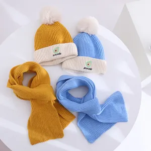 Detail of knit children's hat and scarf set with avocado patch and soft faux fur pom-pom