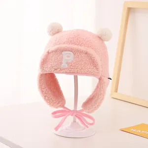 Detailed close-up of a pink plush winter hat with earflaps and a white embroidered P letter