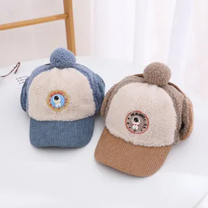 Dettaglio di cappelli invernali per bambini in velluto con pompon e paraorecchie