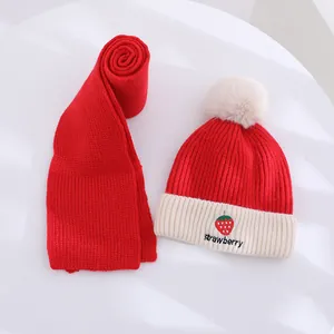 Close-up of winter knit hat with strawberry embroidery and soft fluffy pompom details