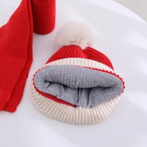 Detail of red and white knitted winter hat showing warm grey lining and plush faux fur pom