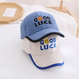 Close-up of plush baseball caps with Good Luck embroidery and smile patches in two colors