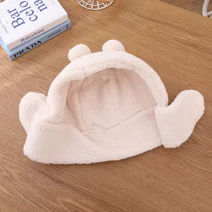 Vue détaillée du bonnet en peluche beige pour enfant avec oreilles sur fond en bois