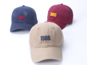 Three retro washed cotton baseball caps in navy, burgundy and khaki with 1985 embroidery