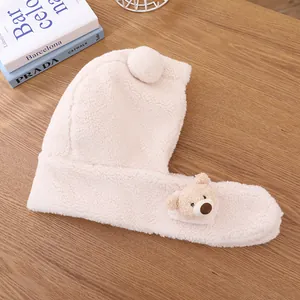 Gros plan du bonnet ours en peluche avec texture sherpa douce sur fond de bois clair