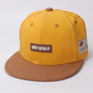 Detail of kids baseball cap with yellow fabric, brown brim, and silicone letter patch