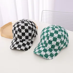 Close-up of kids' checkerboard baseball caps with smile faces in black and green colors