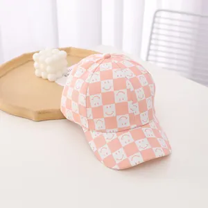 Close-up of pink checkered baseball cap with white smiley face patterns and canvas texture