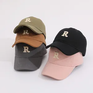 Detail of colorful cotton kids baseball caps featuring embroidered letter R in five shades