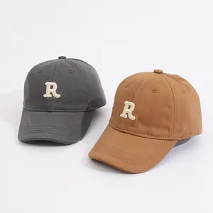 Detail of embroidered R logo on dark gray and khaki cotton baseball caps for kids