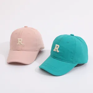 Detail of pink and green cotton baseball caps with textured letter R embroidery