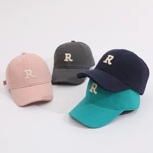 Close-up of cotton baseball caps with embroidered R letters in pastel candy colors