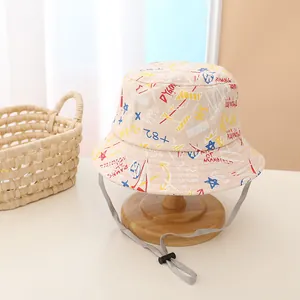 Détail d'un chapeau soleil beige en toile pour enfant avec motifs graffiti et cordon réglable