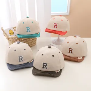 Detail view of colorful soft-brim baby baseball caps with R letter embroidery in various colors