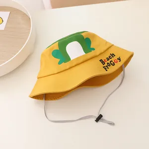 Detail of yellow kids bucket hat with frog print and adjustable chin strap on wooden tray