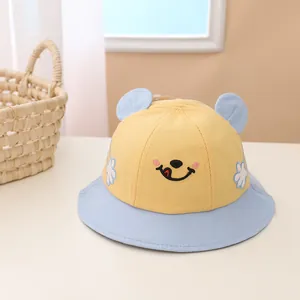 Close-up of baby sun hat with cute smile embroidery and 3D ears on cotton fabric