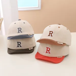 Detail showing four color styles of baby baseball caps with embroidered R letter